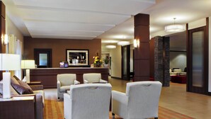 Un hall d’hôtel comprenant un comptoir d’accueil, un espace salon avec des fauteuils et une moquette à motifs.
