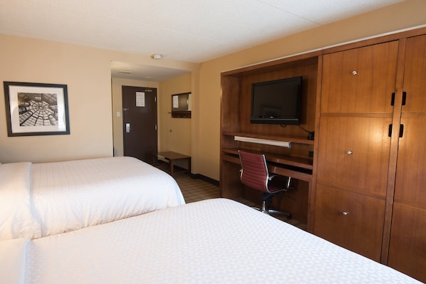 Habitación de hotel con dos camas, un escritorio con silla, televisión y armario.