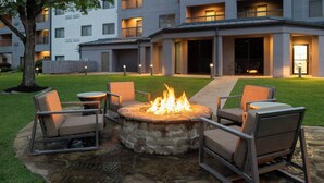 A courtyard with a stone fire pit, outdoor seating, and a building with multiple balconies. - Courtyard by Marriott Shreveport Airport (Shreveport)