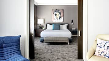 Ein Hotelzimmer mit Bett, Sitzbank, Sessel, einem Bild an der Wand und Teppichboden.