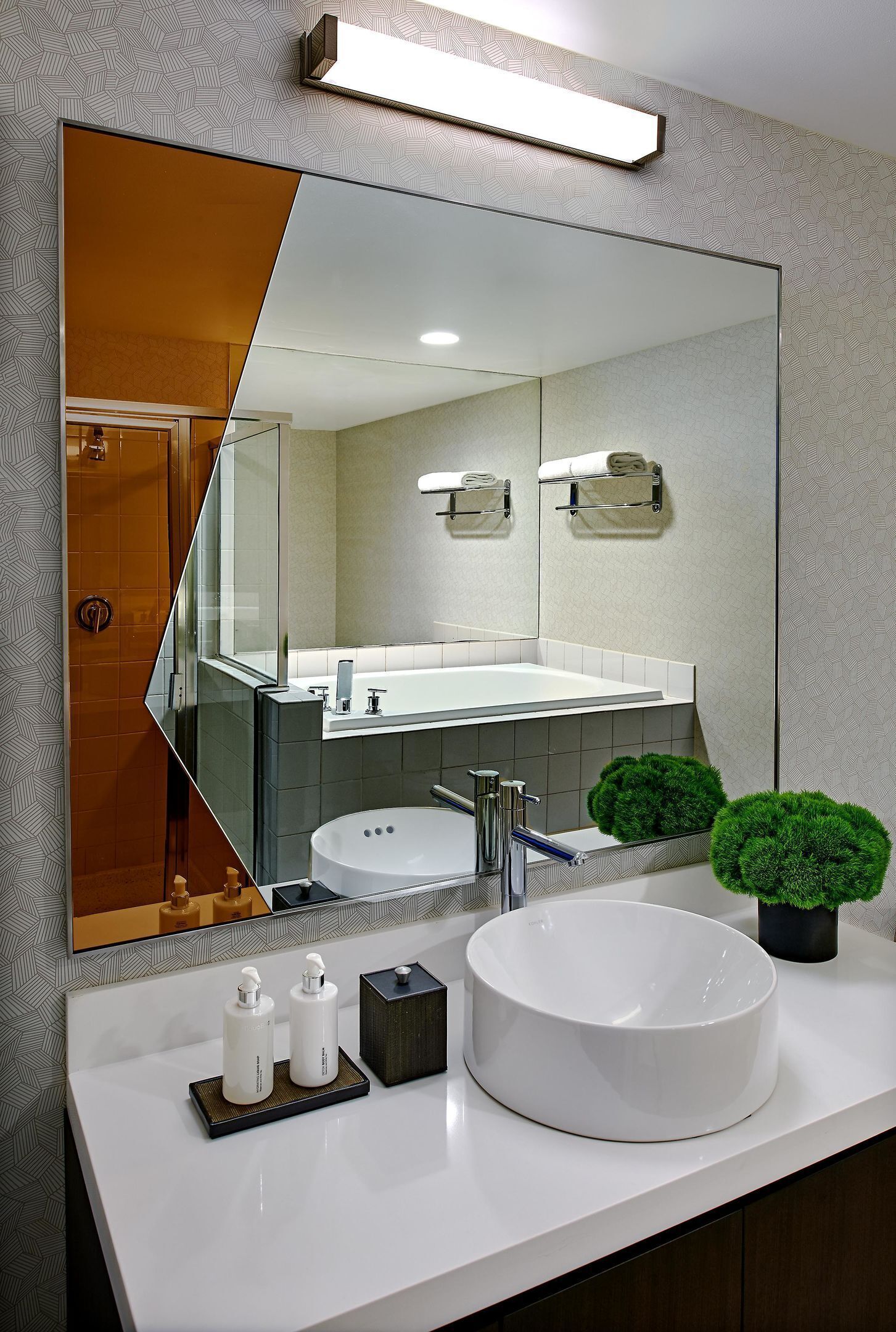 Een moderne badkamer met een grote spiegel, een wit wastafelmeubel en twee groene, bolvormige decoraties.
