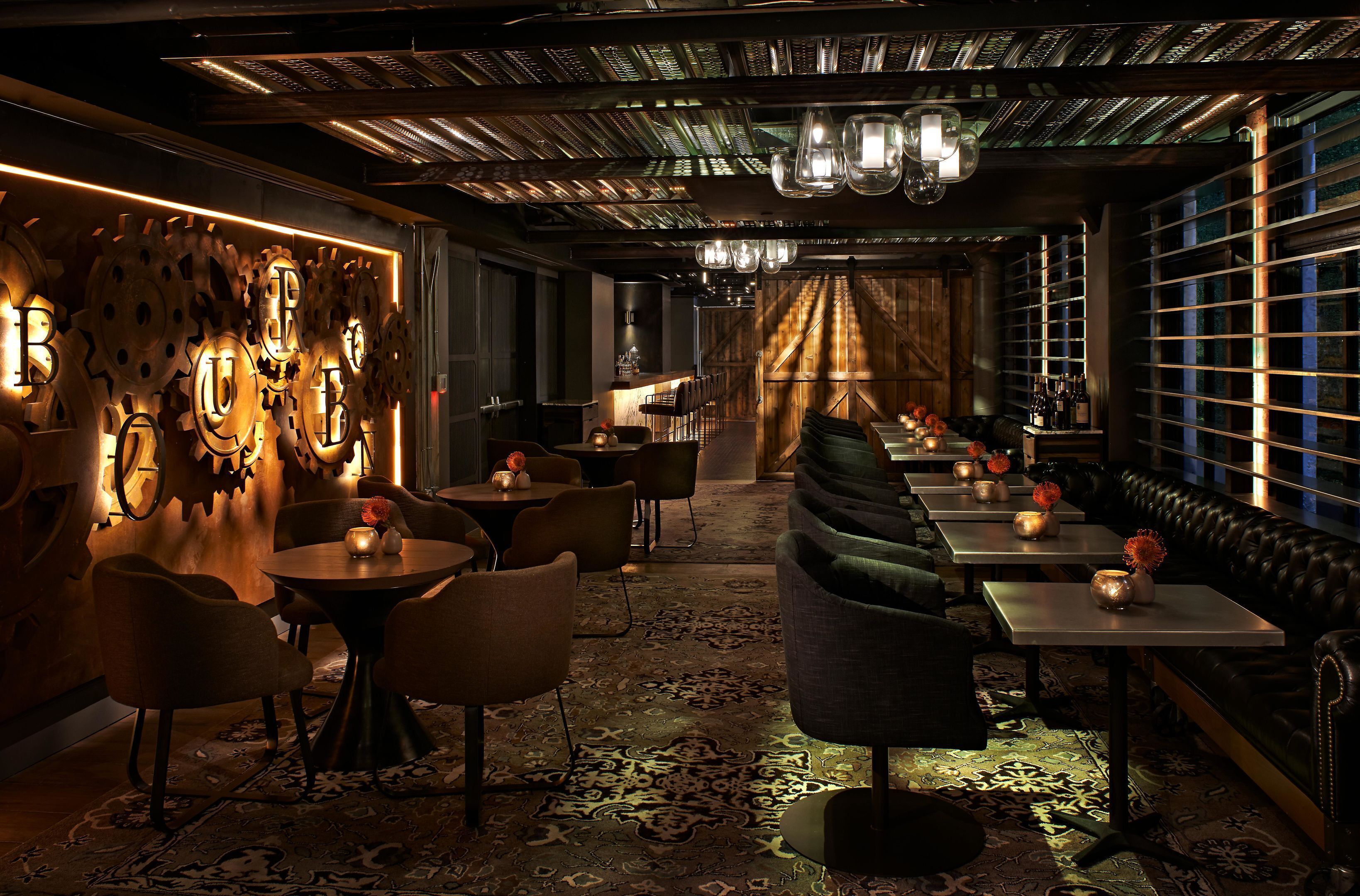 A dimly lit restaurant with a long counter, booths, and a patterned carpet.