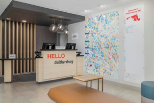Zona de recepción de hotel con un escritorio de madera, un letrero que dice 'HELLO', una computadora y un mapa colorido en la pared.