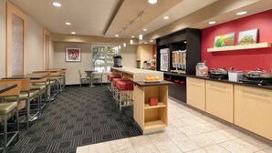 A modern kitchen with a bar area, seating, and a patterned floor. - TownePlace Suites by Marriott Gaithersburg (Gaithersburg)
