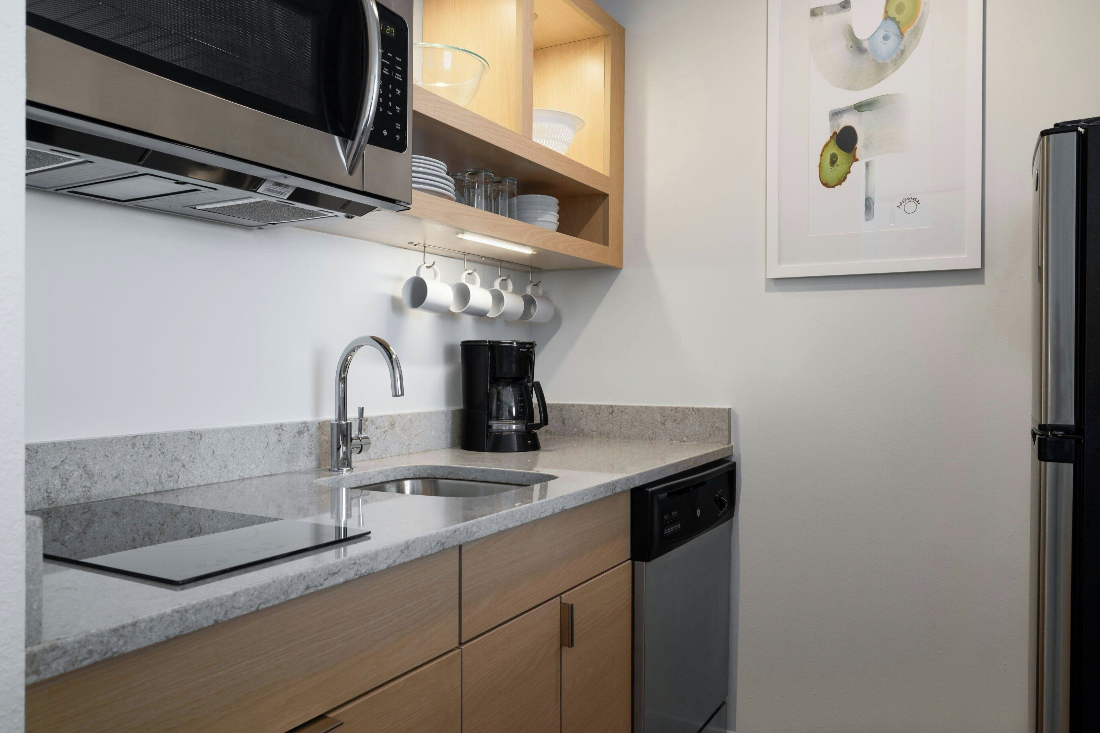 A modern kitchen with a built-in microwave, coffee maker, and dishwasher.