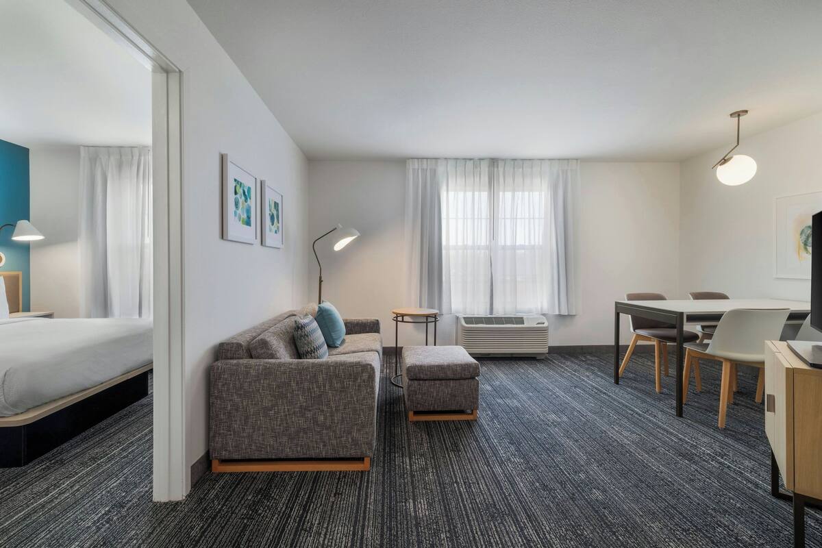 Et hotelværelse med seng, sofa, skammel, skrivebord og stol.