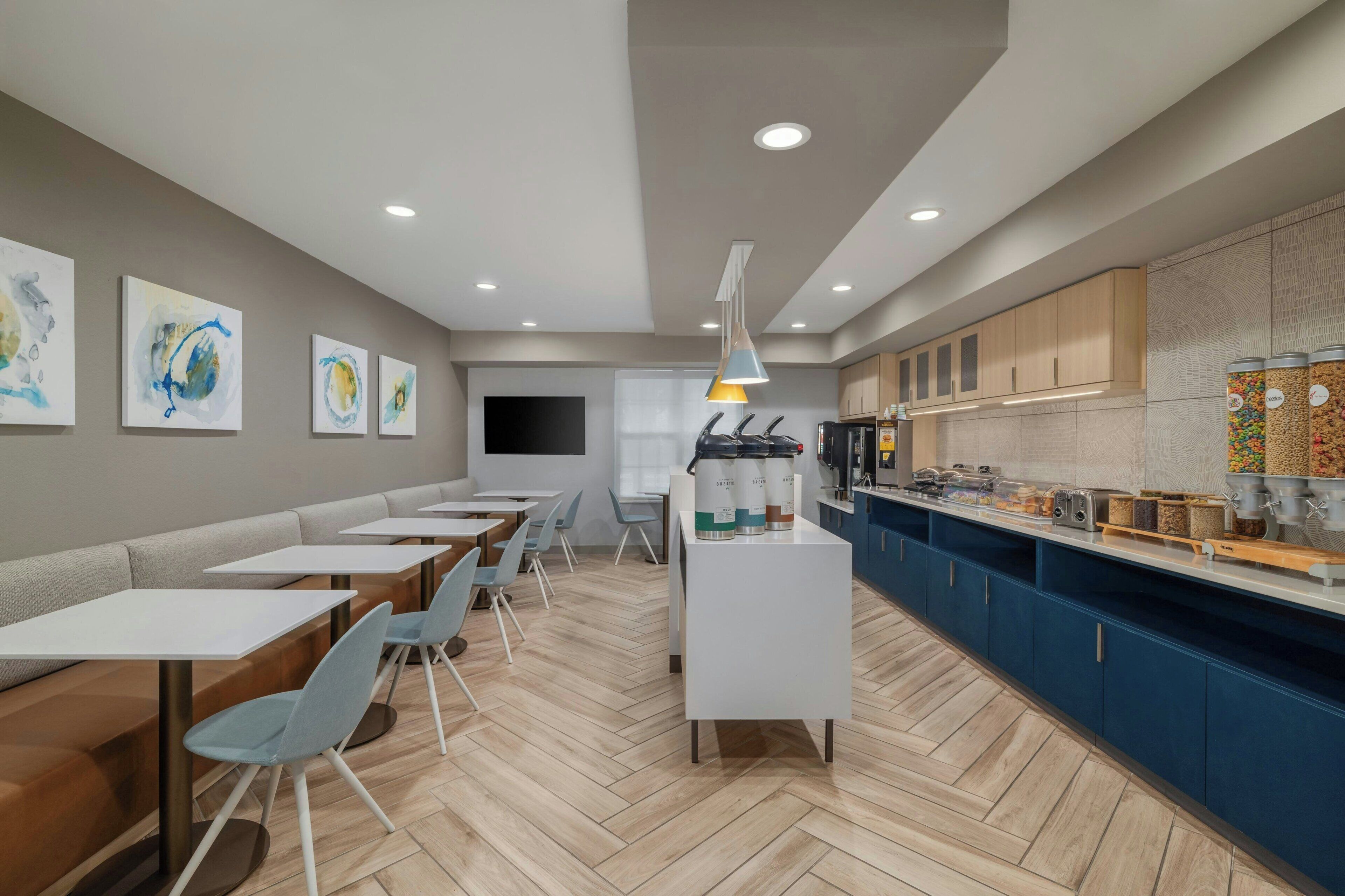 A modern cafe with seating, a counter with food and drink dispensers, and artwork on the walls.