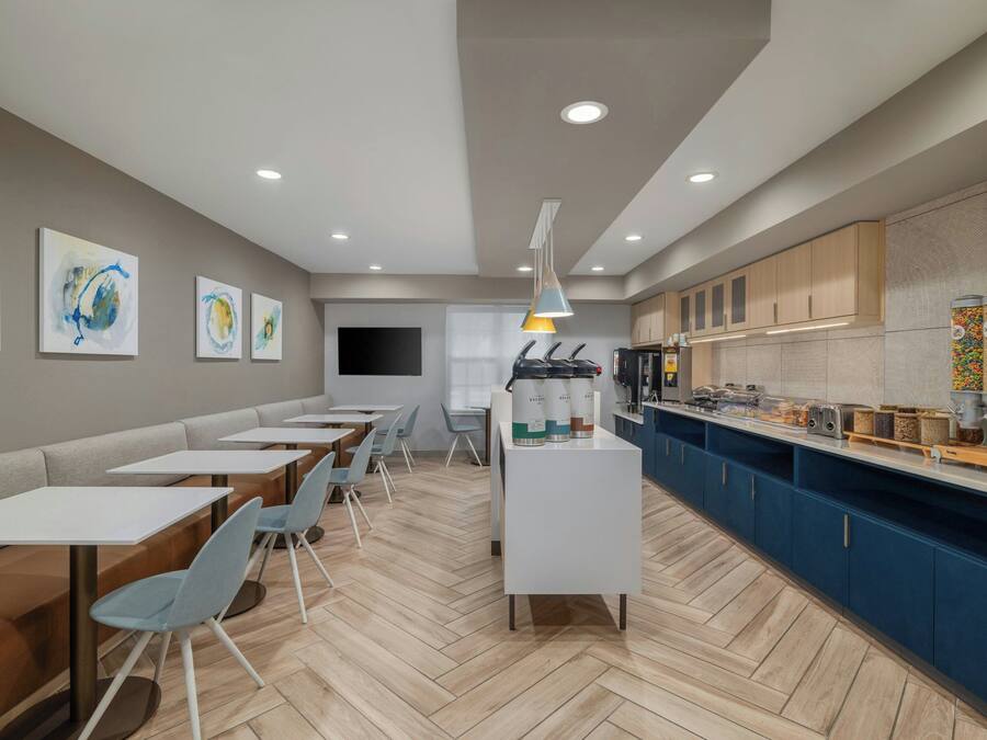 A modern cafe with seating, a counter with food and drink dispensers, and artwork on the walls.