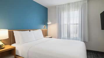 Una habitación de hotel con una cama, una mesita de noche, una lámpara, un televisor y una ventana con cortinas.