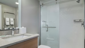 Un baño moderno con ducha de vidrio, lavamanos con encimera de mármol y retrete.