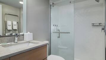 A modern bathroom with a glass-enclosed shower, a sink with a marble countertop, and a toilet.