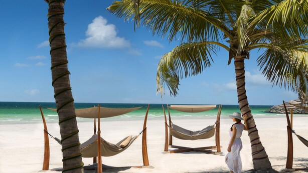 A beach with hammocks and palm trees. - Dusit Ajman Resort & Villas (Ajman)