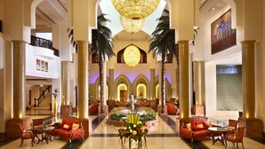 A grand lobby with a central fountain, red sofas, and a chandelier.