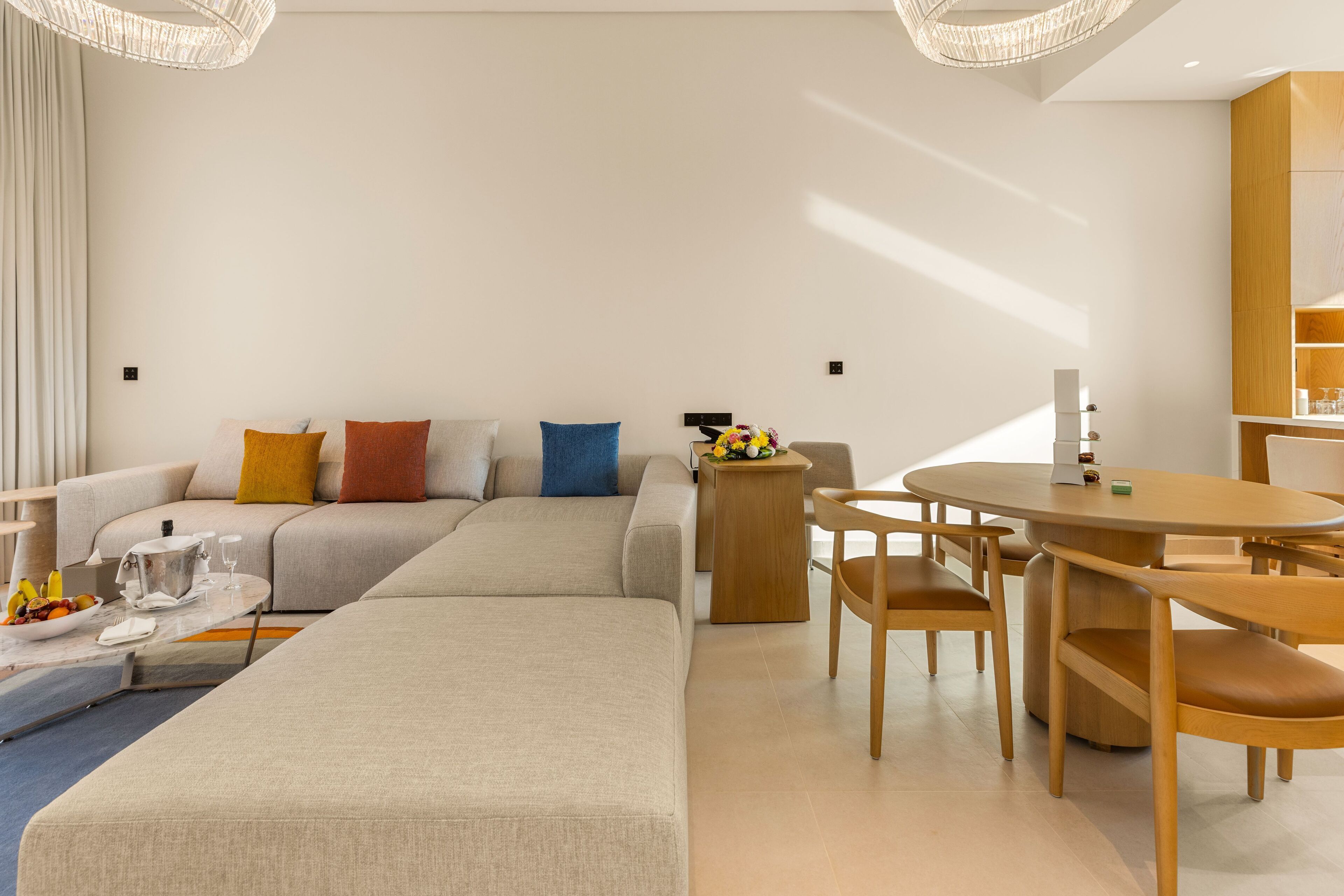 Un salon moderne avec un canapé, une table à manger et des chaises, ainsi qu’une petite table d’appoint sur laquelle est posé un vase de fleurs.