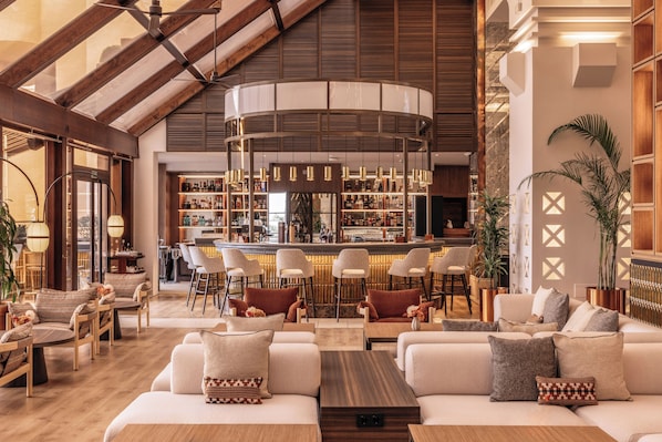 A spacious lounge area with a bar, seating arrangements, and a high ceiling with exposed beams. - Hacienda del Mar member of Meliá Collection (Estepona)