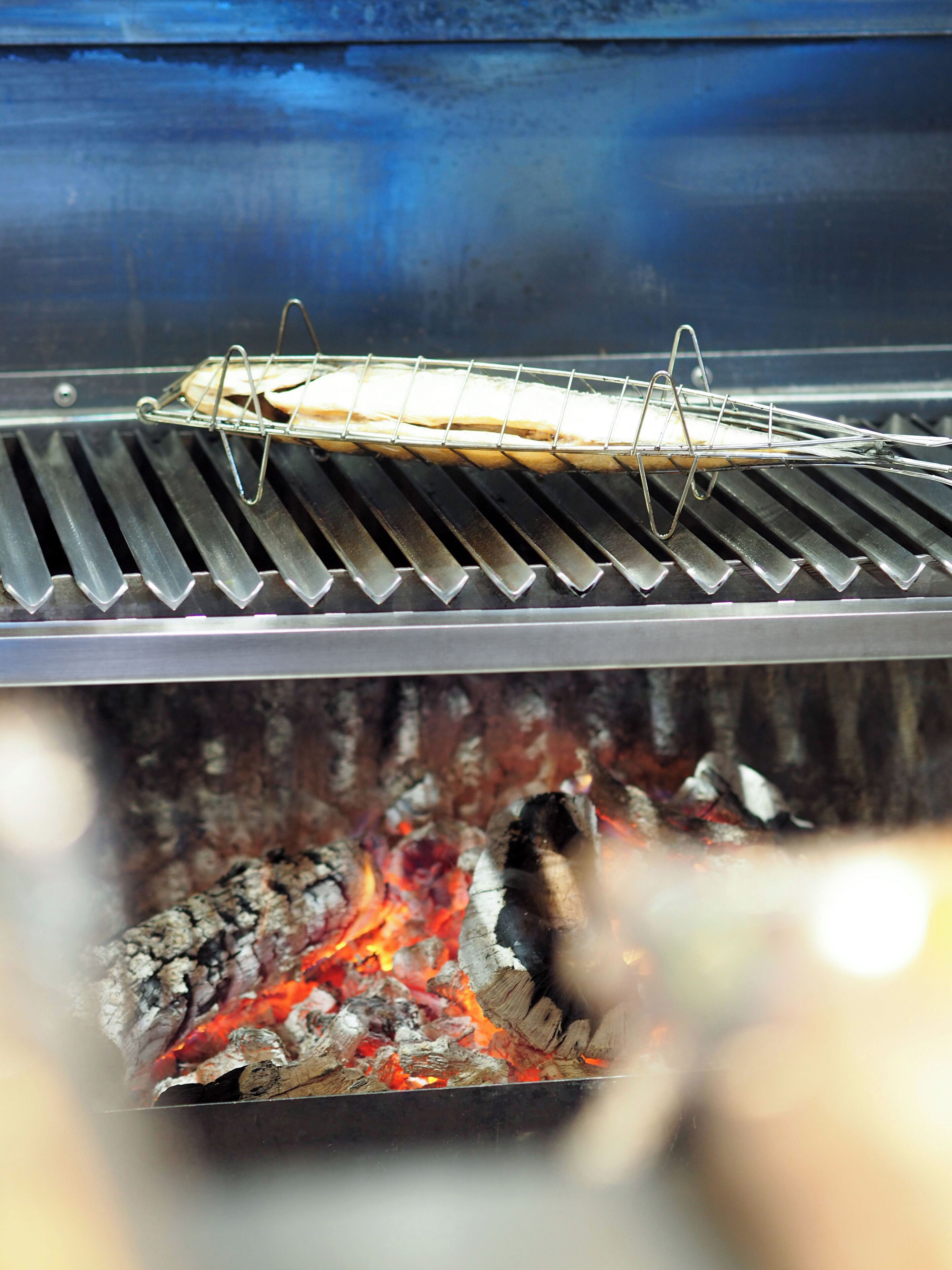 Una parrilla con una rejilla de metal sosteniendo una masa plana sobre fuego.