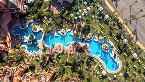 An aerial view of a resort with multiple swimming pools, sun loungers, and palm trees. - Hacienda del Mar member of Meliá Collection (Estepona)