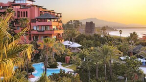 A resort with a swimming pool, palm trees, and a view of the ocean. - Hacienda del Mar member of Meliá Collection (Estepona)