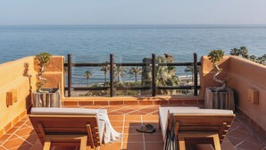 A terrace with a view of the sea, wooden lounge chairs, and potted plants. - Hacienda del Mar member of Meliá Collection (Estepona)