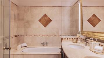 Un baño con bañera, dos lavamanos, un espejo y artículos de aseo.