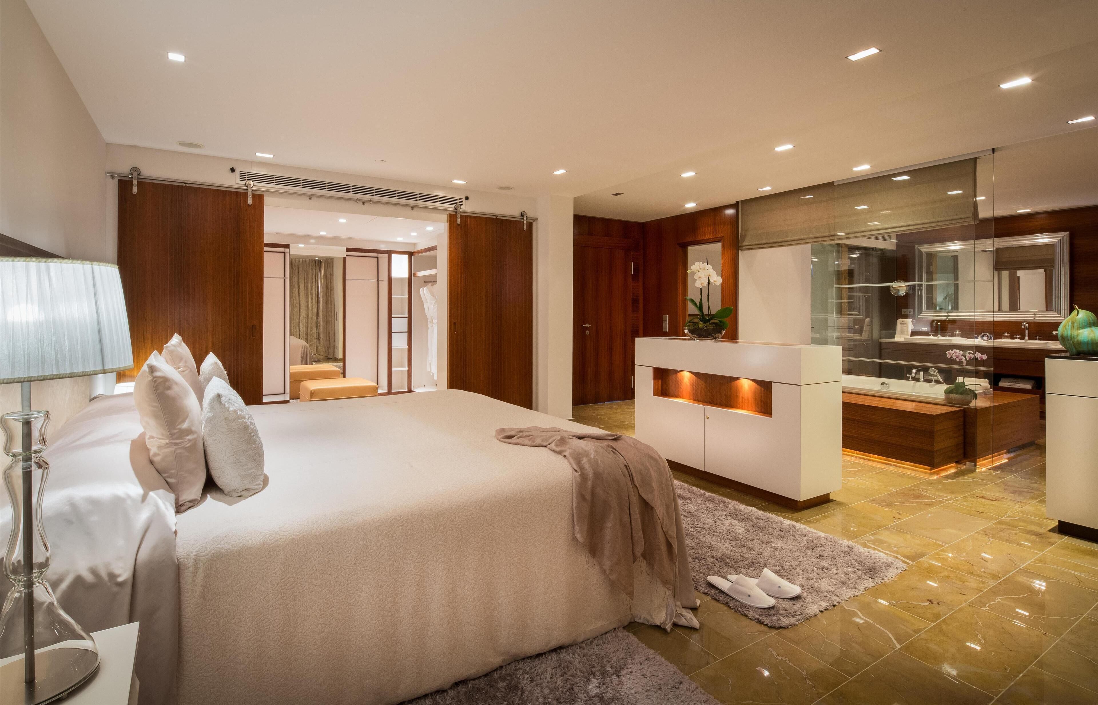A modern bedroom with a large bed, a vanity with a mirror, and a walk-in closet.
