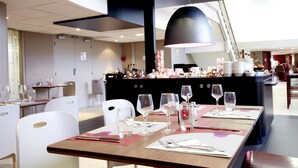 Un restaurant moderne avec des tables dressées pour le service, un bar central et un design contemporain au niveau du plafond.