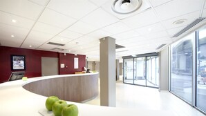 Un espace d’accueil moderne, doté d’un comptoir incurvé, d’un écran numérique et d’une présentation de pommes vertes.
