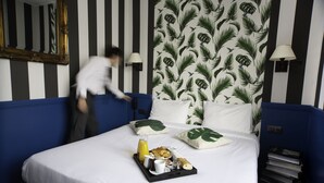 A hotel room with a bed, a tray of breakfast items, and a mirror on the wall.