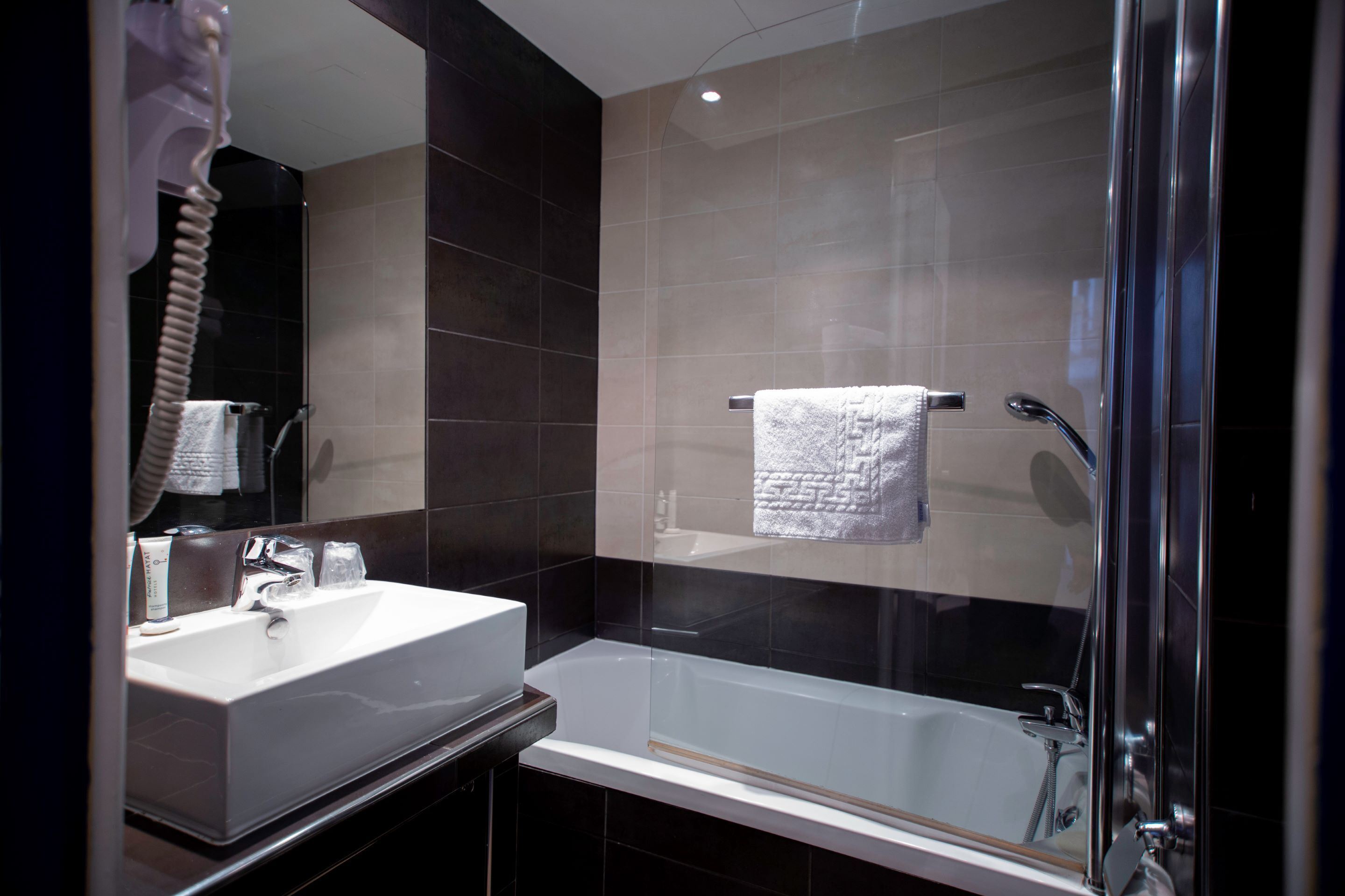 Une salle de bain moderne avec une grande baignoire, un lavabo blanc et une douche à parois de verre.