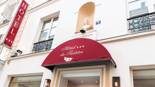 A hotel entrance with a red awning displaying "Hotel du Théâtre" and a "HOTEL" sign above.