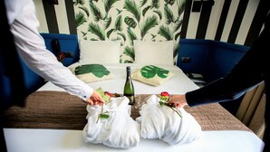 A hotel room with a bed, pillows, and a bottle of champagne.