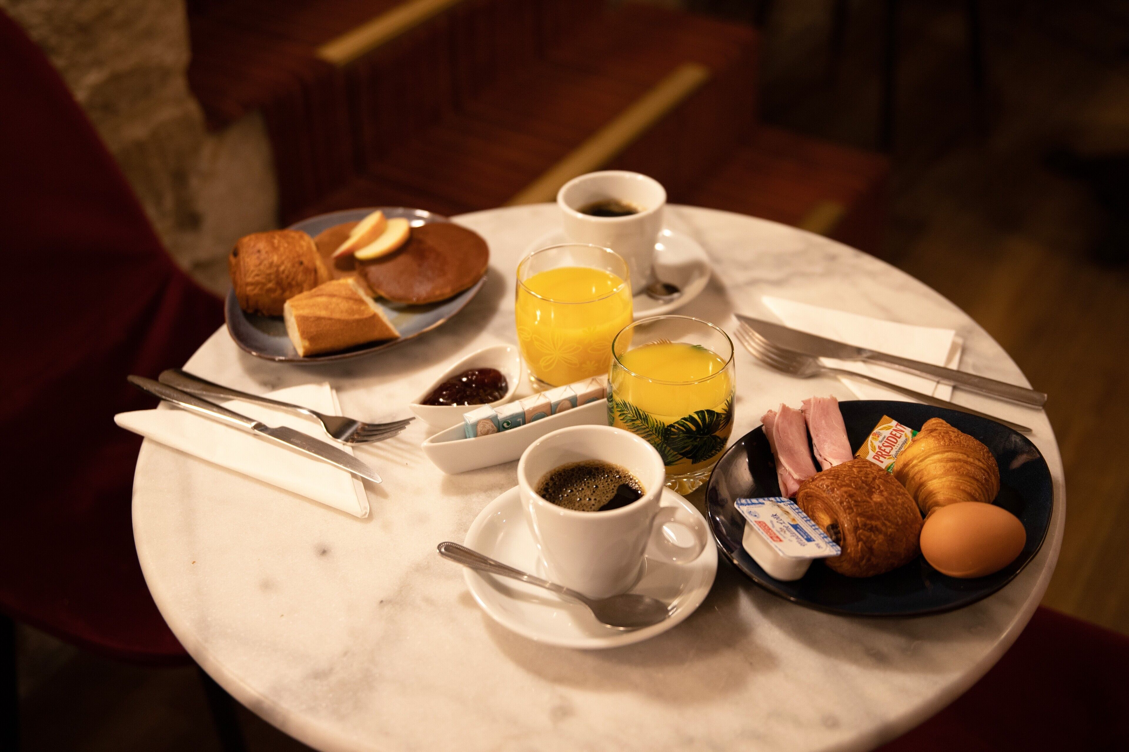 A breakfast table with croissants, eggs, juice, and coffee.