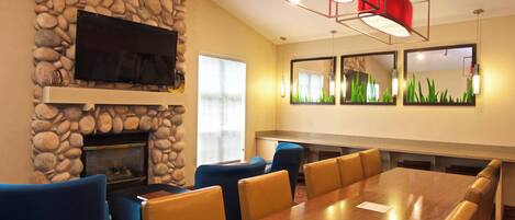 A conference room with a stone wall, a fireplace, a large table, and blue chairs.