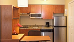 Une cuisine compacte dotée de meubles en bois, d’un four à micro-ondes, d’un réfrigérateur, d’une machine à café et d’un évier.