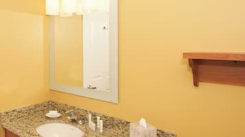 Une salle de bain avec un lavabo en granit, un miroir et un meuble à pharmacie en bois.