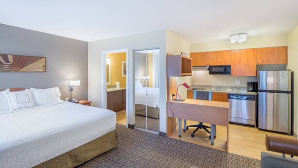 Une chambre d’hôtel comprenant un lit, un bureau, une kitchenette et une salle de bain.