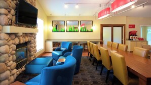 Un salon moderne doté d’une cheminée en pierre, de sièges bleus, d’une table à manger en bois et d’un téléviseur à écran plat fixé au mur.