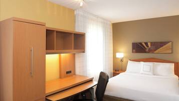 A hotel room with a bed, desk, chair, and a wardrobe.