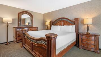 Una habitación de hotel con una cama grande, dos mesitas de noche con lámparas, un aparador y un espejo.