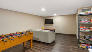 Relax in this cozy space with a foosball table, sofa, and bookshelf filled with board games.