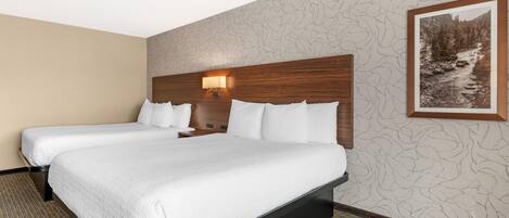 Habitación de hotel con dos camas, cabecero de madera, lámpara de pared e imagen enmarco de un paisaje.