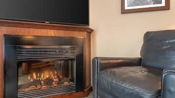 Una chimenea de diseño moderno, un sillón de cuero negro y un cuadro en la pared.