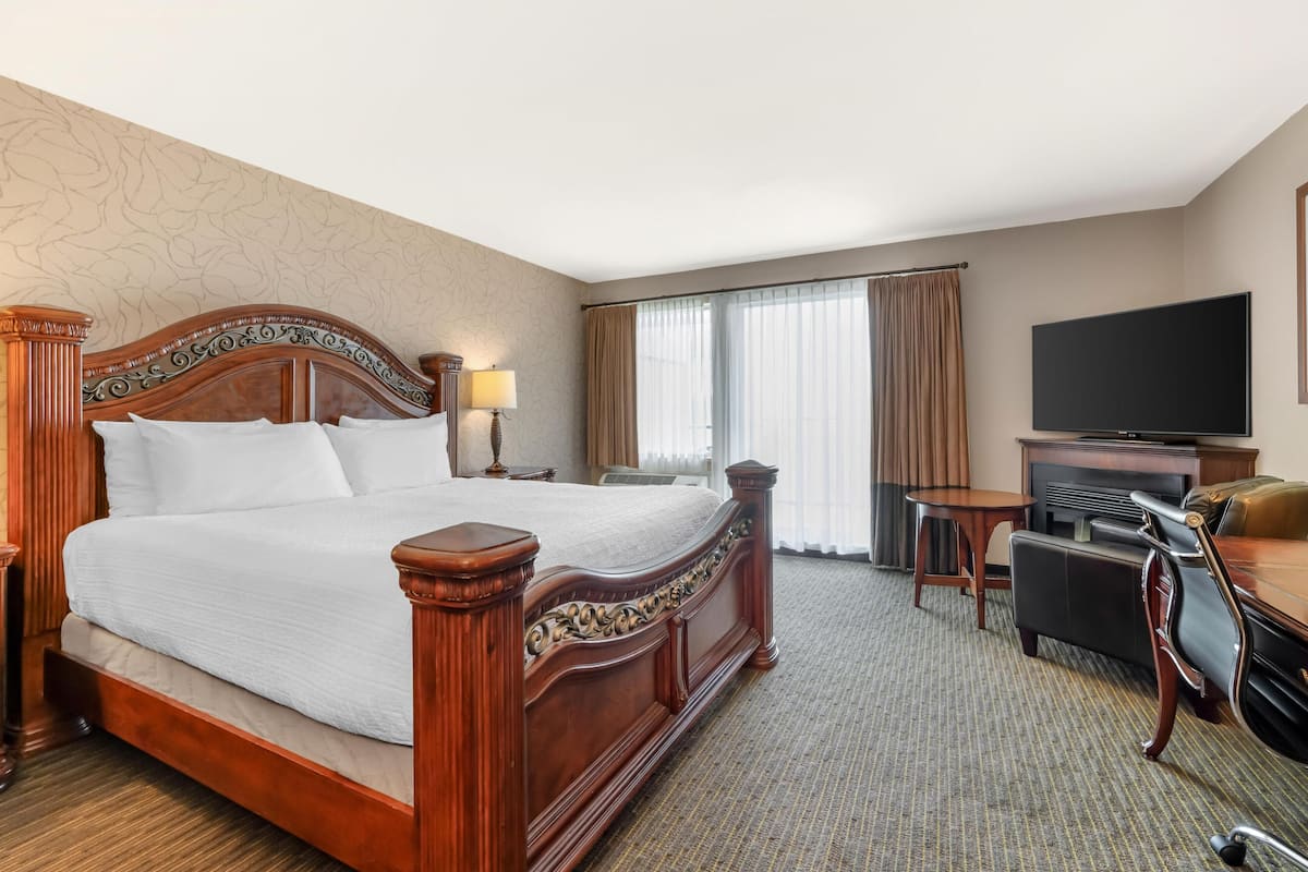 Una habitación de hotel con una cama grande, televisión, escritorio y una silla.