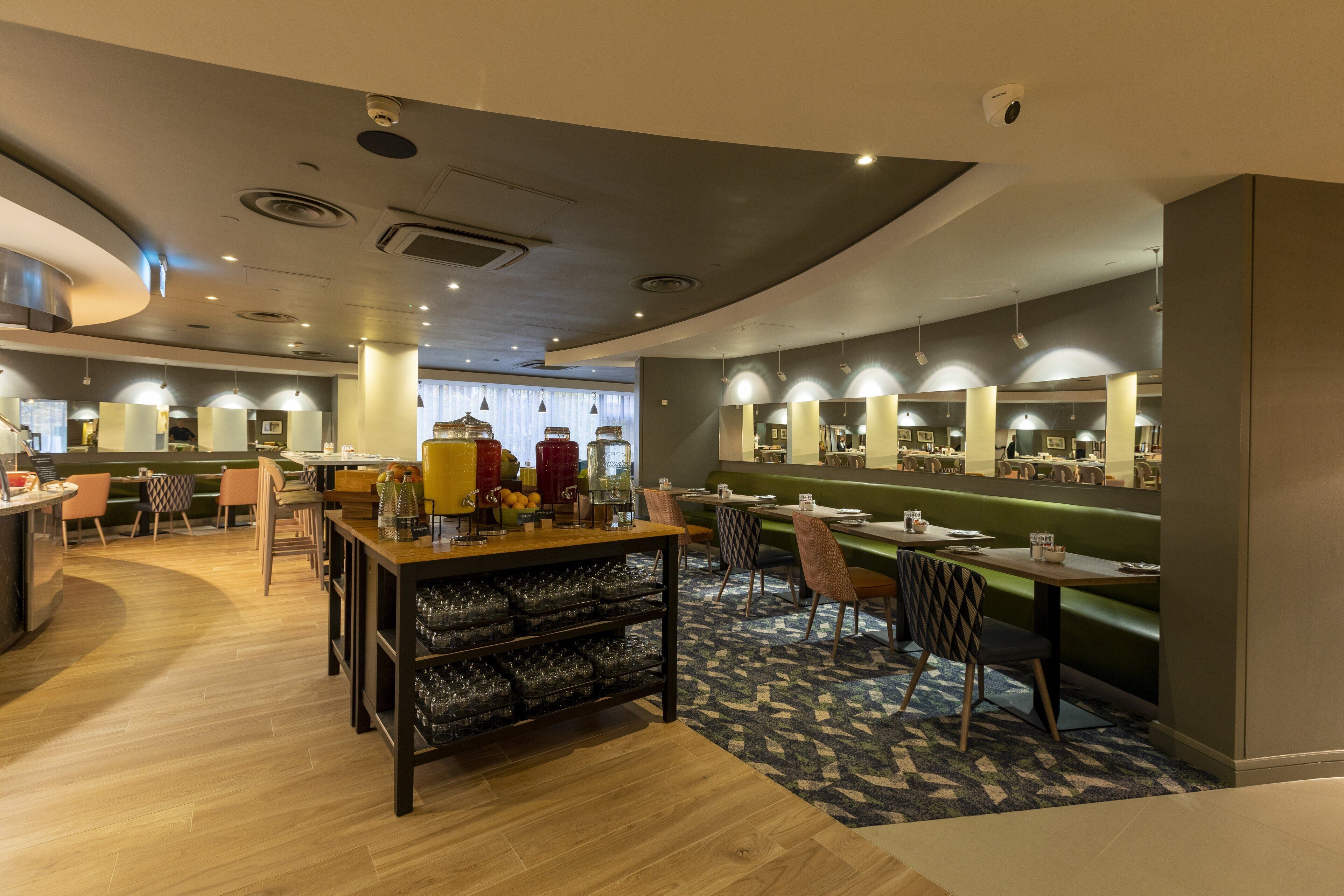 A modern restaurant with a central bar area, seating arrangements, and a patterned carpet.