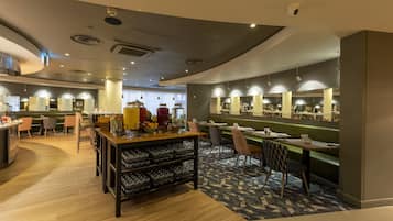 A modern restaurant with a central bar area, seating arrangements, and a patterned carpet.