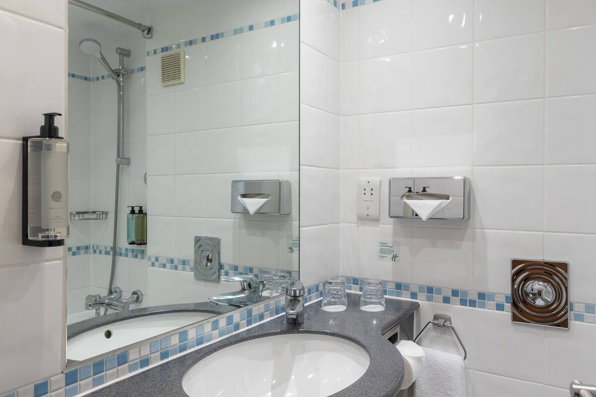 A modern bathroom with a granite sink, white toilet, and a large mirror.