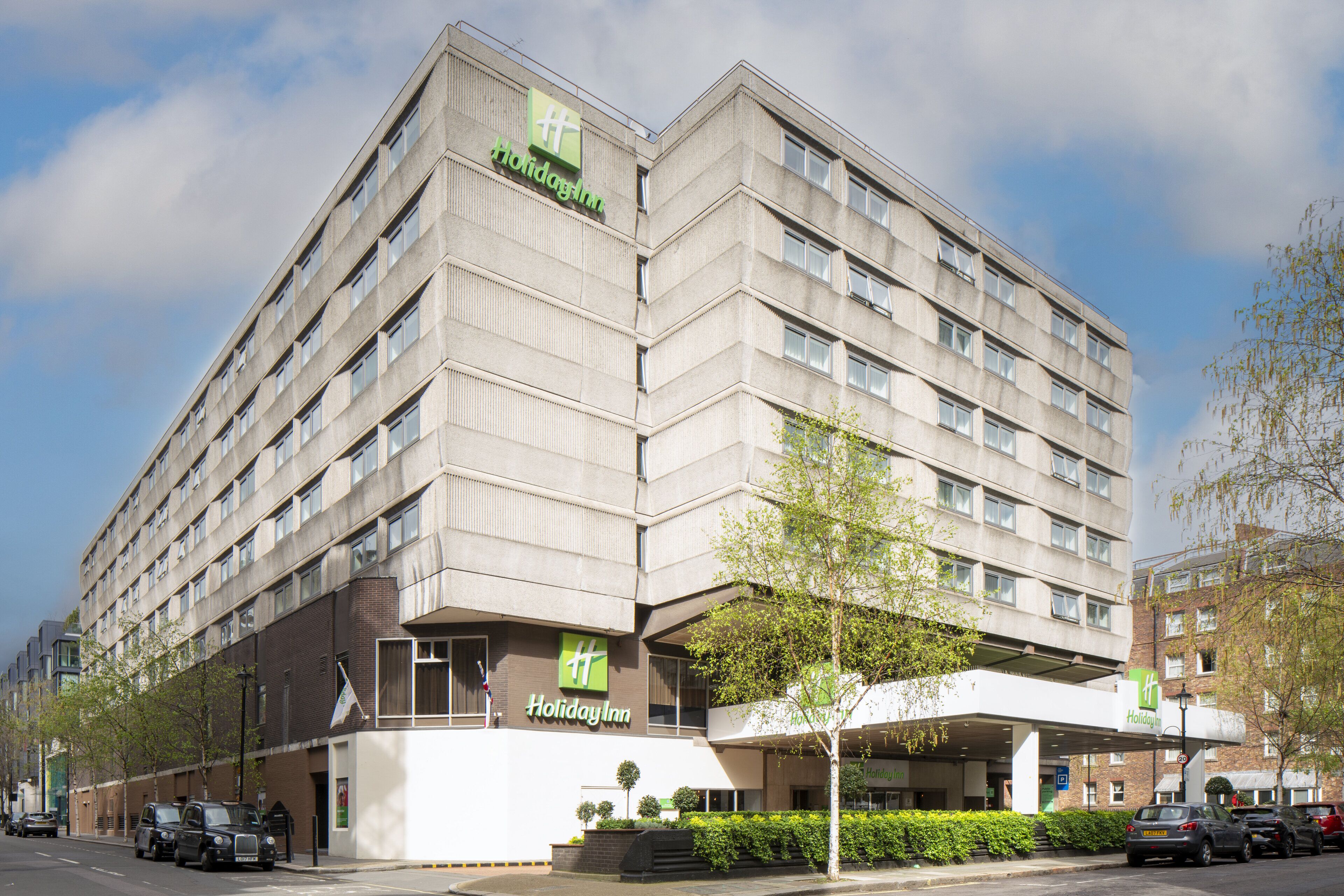 A multi-story Holiday Inn hotel with a modern design, featuring a prominent green logo and a covered entrance.