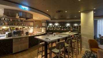 En modern restaurang med en böjd bardisk, flera sittgrupper och en tydligt synlig utrymningsskylt.