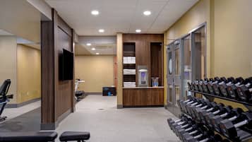 A gym with exercise equipment, a television, and a reception desk.