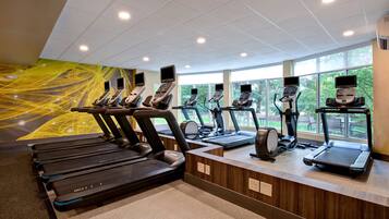 Un gimnasio con múltiples cintas de correr y bicicletas estáticas, ventanas amplias y un diseño moderno.